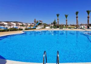 une grande piscine bleue avec des palmiers en arrière-plan dans l'établissement Alquileres Figuerola Los Abanicos, à Peñíscola 62 autres photos