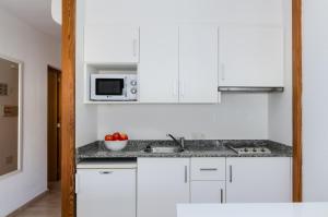 a white kitchen with a sink and a microwave at Apartamentos venecia a unos pasos de la playa in Port d'Alcudia