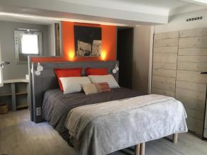 a bedroom with a bed with an orange wall at La 54 Provence in LʼIsle-sur-la-Sorgue