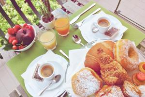 a table topped with plates of pastries and cups of coffee at Hotel Aria di Mare Bed & Breakfast & Beach in centro a Riccione in Riccione