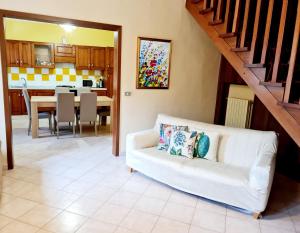 a living room with a white couch and a kitchen at Casa Colonna in Montegrotto Terme