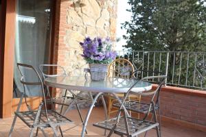 a glass table with chairs and a vase of purple flowers at Podere La Tona in Gavorrano