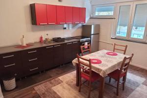 uma cozinha com uma mesa e uma cozinha com armários vermelhos em Apartman Banja Luka 2 em Banja Luka