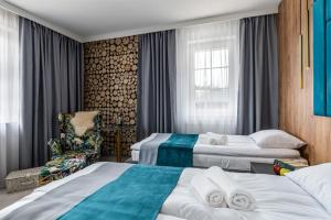a hotel room with two beds and a chair at Zamkowe Apartamenty in Sandomierz