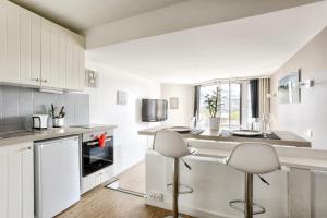 a kitchen with white cabinets and stools in it at Deauville-Port - Escapade Deauvillaise dans un charmant studio in Deauville