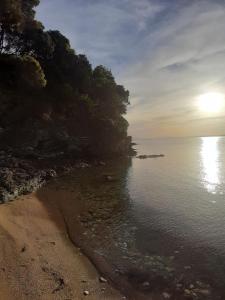 a beach with the sun rising over the water at Koutadelias rooms in Kalamos