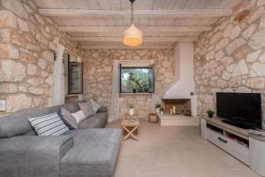 a living room with a couch and a tv in a stone wall at Ionio Villa Elia in Vasilikos
