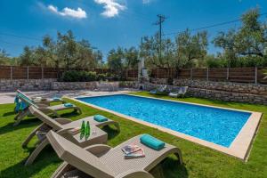 a backyard with a swimming pool with lawn chairs at Ionio Villa Elia in Vasilikos