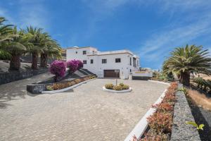 a house with palm trees and flowers in a driveway at Finca Bellavista in Teguise