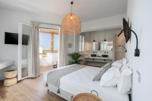a bedroom with a white bed and a kitchen at Sunday Luxury Suites in Agia Anna Naxos