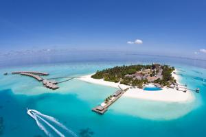 an island in the ocean with a boat in the water at Velassaru Maldives in South Male Atoll