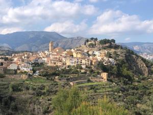 a village on a hill with mountains in the background at Casa El Castellet en Polop. in Polop