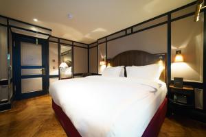 - une grande chambre avec un grand lit et des oreillers blancs dans l'établissement Mimi's Hotel Soho, à Londres