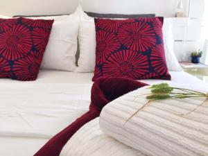 een wit bed met rode en blauwe kussens erop bij PIGNETO VILLAGE Roma Guest House Apartment in Rome
