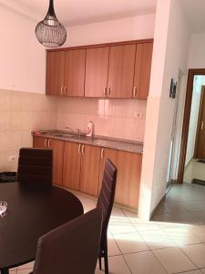 eine Küche mit Holzschränken und einem Tisch mit Stühlen in der Unterkunft Guest House Ondine in Shëngjin