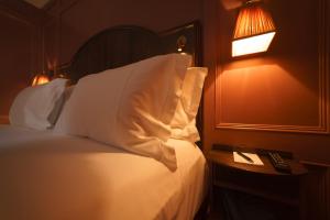 a bedroom with a bed with white pillows and a lamp at Mimi's Hotel Soho in London