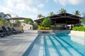 uma piscina num resort com cadeiras e um guarda-sol em Trupial Hotel & Casino em Willemstad