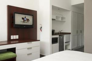a kitchen with a refrigerator, stove, sink and a television at Trupial Hotel & Casino in Willemstad
