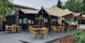 un patio al aire libre con mesas, sillas y sombrillas en Grand Café Goejje voorheen Oranje Hotel en Meijel