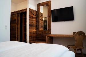 um quarto com uma cama, uma televisão e um espelho em Hotel Almwirt em Haar