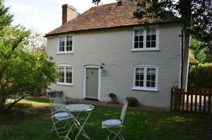 a table and chairs in front of a white house at Oast Barn Cottage by Bloom Stays in Faversham