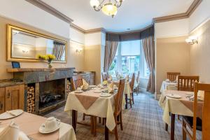 a dining room with tables and a fireplace at Avondale Guest House in Keswick