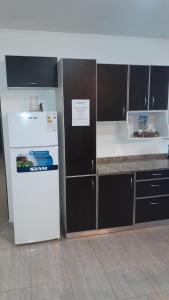 Una cocina con un refrigerador blanco y gabinetes marrones. en San Luis Centro, en San Luis