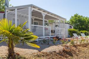 a white house with a porch and some plants at Zelena Laguna Mobile Homes in Poreč
