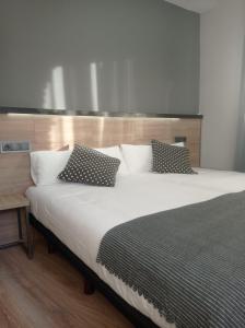 a bedroom with a large white bed with pillows at Alda Centro Pamplona in Pamplona
