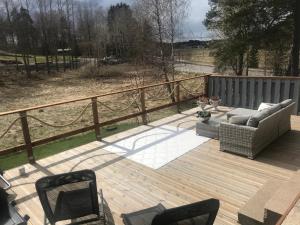 une terrasse en bois avec deux chaises et un canapé. dans l'établissement Tyylikäs rivitaloasunto Lohjalla, à Lohja