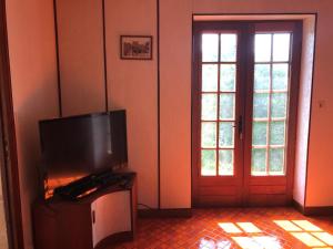 a living room with a flat screen tv and a door at May's Cottage in Availles-Limouzine
