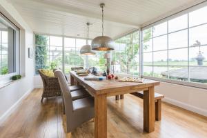 ein Esszimmer mit einem Holztisch und Fenstern in der Unterkunft Fährhauslodges Natur in Sicht in Norden