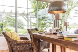 a dining room with a table with books and chairs at Fährhauslodges Natur in Sicht in Norden