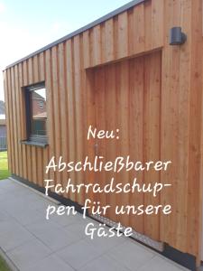 een houten hek met de woorden nieuwe architectonische barrière regen scheur universum poort bij Greenments, Apartments für Freizeit und Beruf in Geesthacht