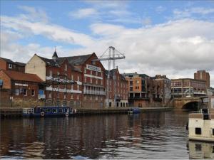 a city with buildings and a river with boats at Woodsmill Quay Apartments in York