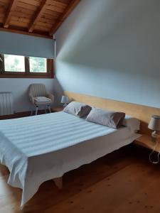 una camera con un grande letto bianco e una sedia di CASA RURAL AINGERU NATURALEZA Y MONTAÑA a Oñati
