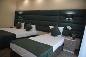 キテンにあるHotel Nevaのホテルルーム ベッド2台&緑のヘッドボード付