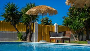 a chair and umbrella next to a swimming pool at Mr Ziggy's Surfhouse in Costa da Caparica