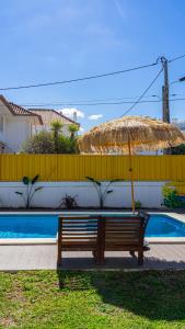 un banc avec un parasol à côté de la piscine dans l'établissement Mr Ziggy's Surfhouse, à Costa da Caparica