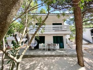 a white house with a table and chairs at Family Resort Urania in Baška Voda