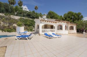 een villa met een zwembad en blauwe ligstoelen bij Villa Empedrola in Calpe
