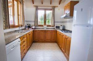 een keuken met houten kasten en een witte koelkast bij Villa Empedrola in Calpe