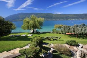 een uitzicht op een meer met stoelen en een boom bij Villa Le France - Vision Luxe in Veyrier-du-Lac