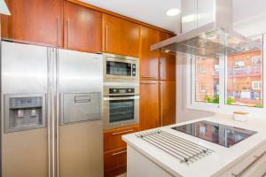 a kitchen with stainless steel appliances and wooden cabinets at HomeHolidaysRentals Amaral in Pineda de Mar