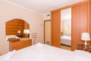 a bedroom with a white bed and a mirror at HomeHolidaysRentals Amaral in Pineda de Mar +44 photos
