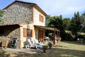 Casa de piedra con 2 sillas y mesa en Cottage Barbara with aircon, beautiful sea view by ToscanaTour en Casale Marittimo