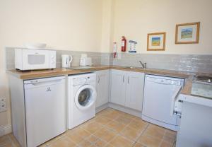 a kitchen with a washing machine and a microwave at Kilkee Holiday Homes Ground Floor in Kilkee