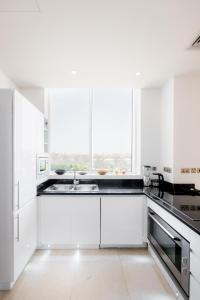 a white kitchen with white cabinets and a sink at Maison Privee - Tiara Diamond G06 in Dubai