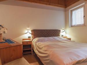 a bedroom with a bed and a nightstand and a window at Casa Cristina in Campitello di Fassa