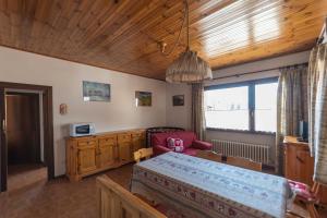 a bedroom with a bed and a couch and a window at Casa Carnevali in Pozza di Fassa